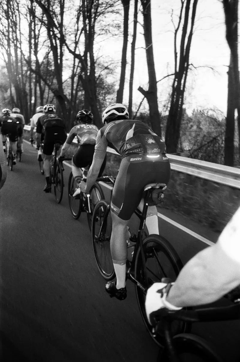 Black and white film photo of a peloton climbing a road race